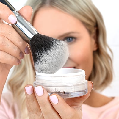 Dip a large powder brush into the product & tap off excess